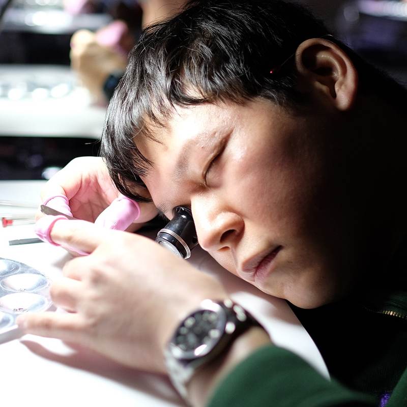 A student wearing an eye loupe concentrates on a movement