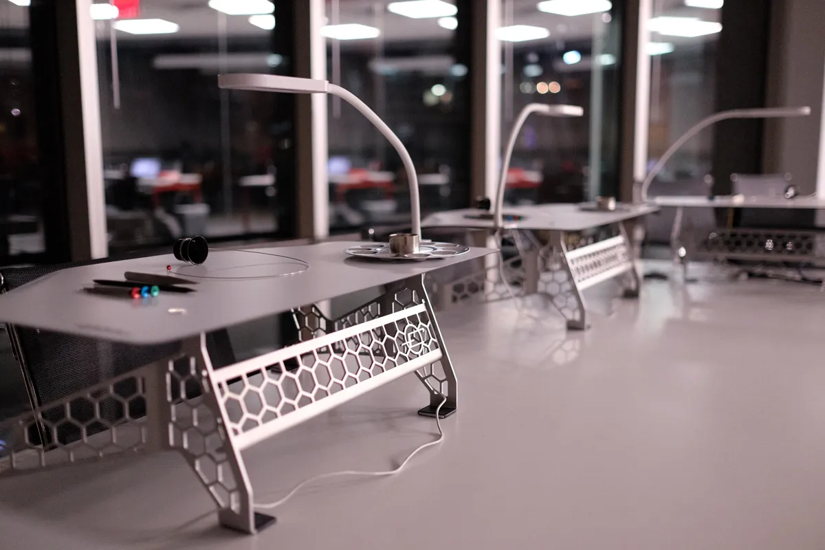Etablee benches set up for a class, each with a lamp, loupe and tools, by a city window at night
