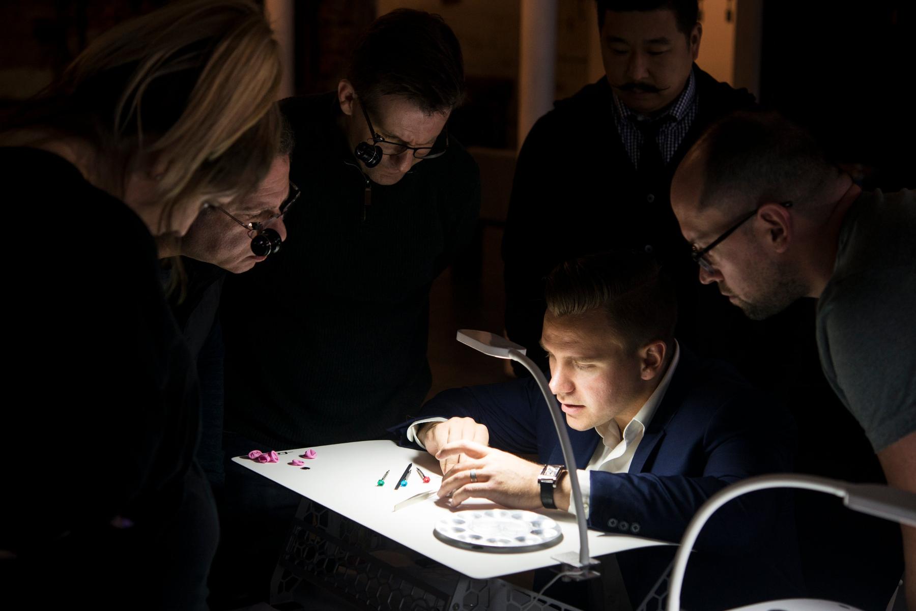 A group gathers around a lit bench as a participant works on a movement