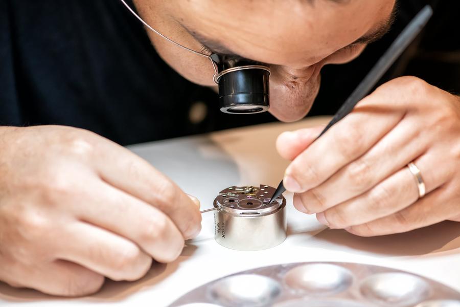 Close-up of a participant with a loupe working on a movement with a pointed tool