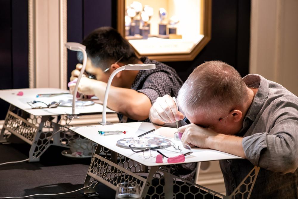 Two participants lean into their work at carbon fibre benches in a boutique