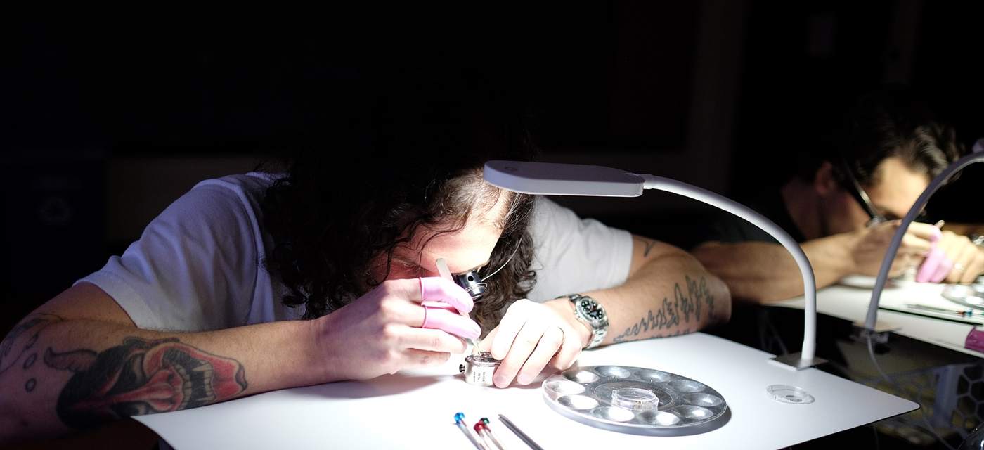 Students at individual watchmaking benches under lamps during an HSNY class