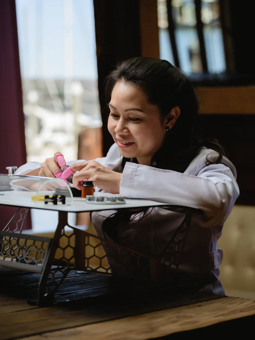 Watchmaker Briana Le working on a movement at the Etablee bench, smiling