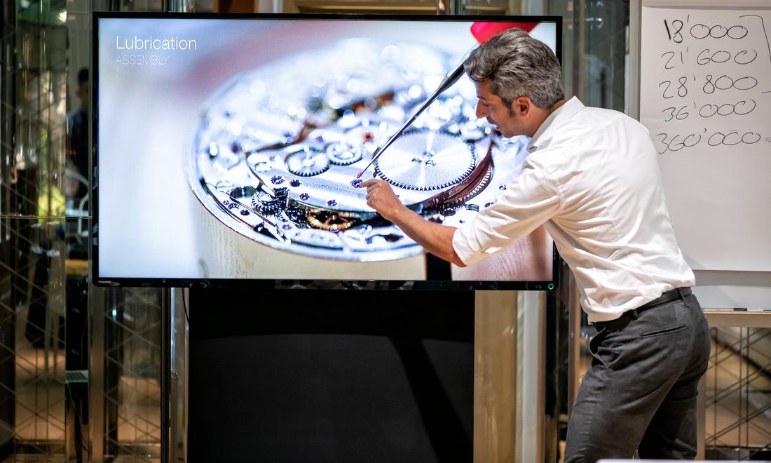 The instructor points to a jewel on a large screen during a lesson on lubrication